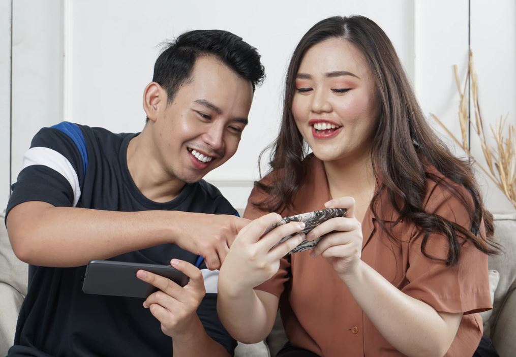 two people interacting with a smart phone, having fun